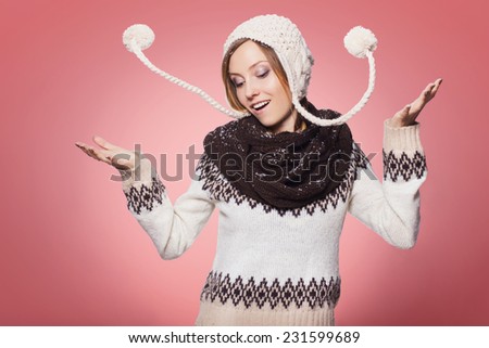 Beautiful redhair woman in winter outfit: warm sweater, scarf and hat with snow all over her. Isolated on pink red
