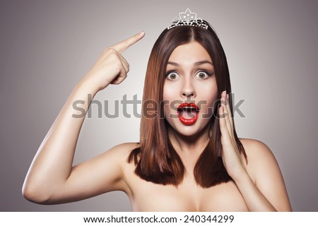 Beauty close up portrait of a brunette woman with red lipstick. Pure skin. Tiara crown diadem on her. Toned image, dark background