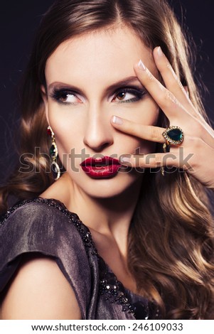 Brunette beautiful luxury woman in dress with clear skin and evening dark make up: green cat eye and brown eyeshadows. Waved hairstyle. Dark background