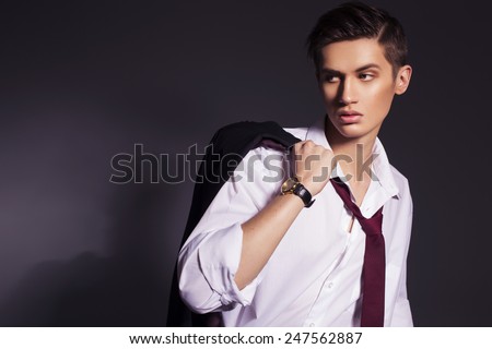 Young handsome men in suit shirt and red tie wear watches looking sideways. dark background. indoors. copy space