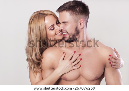 Sexy fit muscled couple in sportswear on neutral grey background hugging