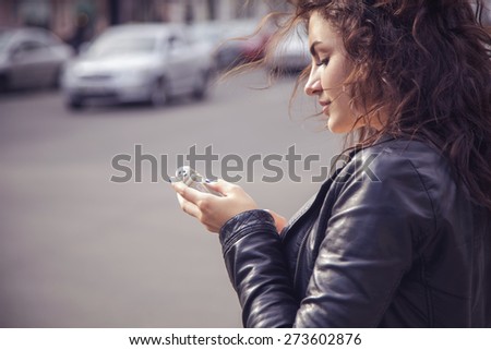 Brunette beautiful stylish caucasian woman in casual outfit on a walk on european city street typing message on her phone. copy space