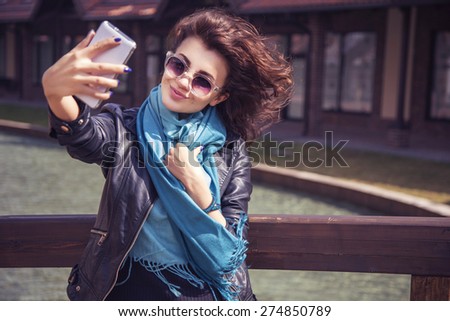 Brunette beautiful stylish caucasian woman in casual outfit on a walk on european city street making selfie on her phone. copy space