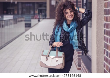 Brunette beautiful stylish caucasian woman in casual outfit on a walk on european city street with designer fashion bag. copy space