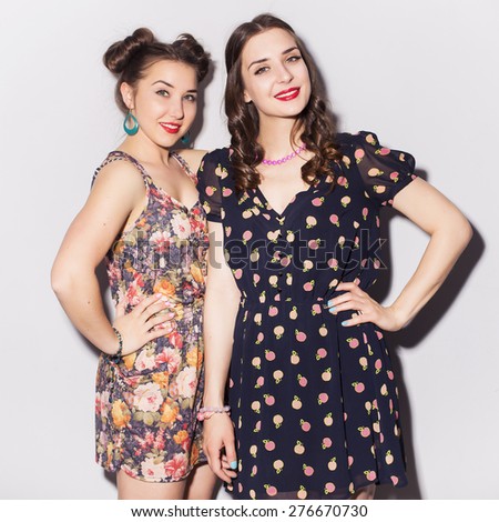 Two beautiful brunette women (girls) teenagers spend time together having fun, make funny faces. Casual hipsters outfit: romantic dresses