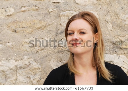 Outdoor portrait of smiling charming young woman against wall