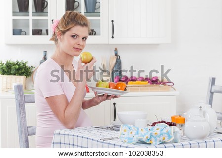 Beautiful pregnant woman with fresh fruit on the  house kitchen.