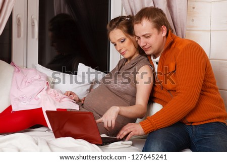 Happy pregnant family with children\'s clothes  sit on a sofa of the house.