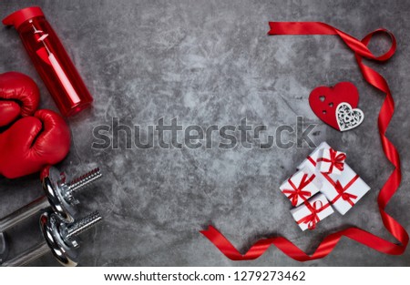 Dumbbells, boxing gloves, bottle for water, gift boxes and red hearts on grey background.Top view with copy space. Valentine\'s Day card. Fitness, sport and healthy lifestyle concept.