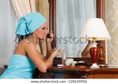 The young woman does a make-up, sitting before a house  dressing table.