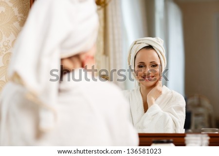 Young woman with cosmetic cream sits before a house  dressing table. Concept body care.