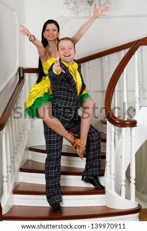 Young cheerful pair in bright clothes of style of a retro on a ladder in a room.