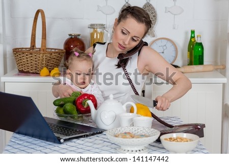 Young mother  with   little child sit at the dining table in the home kitchen.
