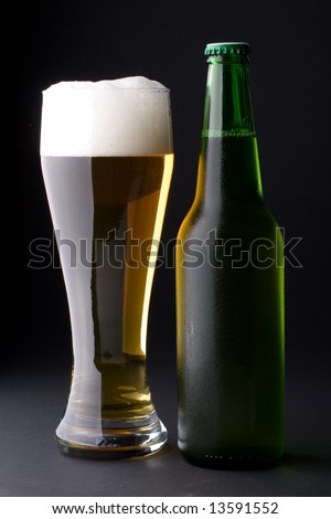 Fresh foamy beer in a glass and a bottle on a black background.