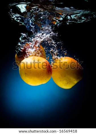 Fresh apricot in water on a black/blue background with air bubbles