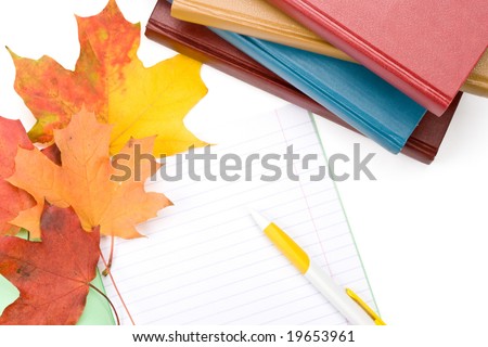 Pile of books, writing-book, pen and autumn leaves on a white background. Concept for \
