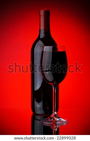 Bottle of a red vintage wine and glass on a red background