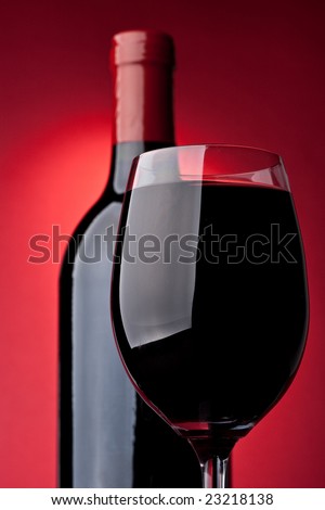Bottle of a red vintage wine and glass on a red background