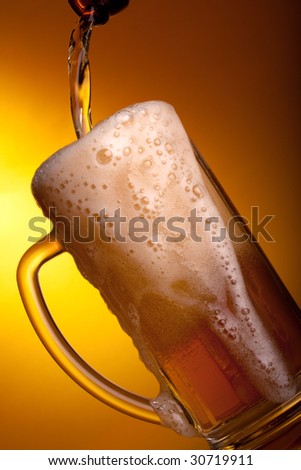 Dark beer pouring into mug on a yellow background.