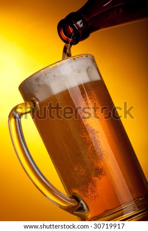 Dark beer pouring into mug on a yellow background.