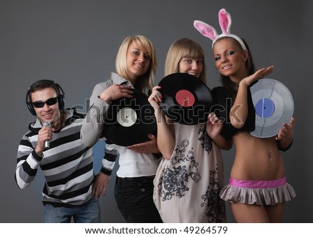 Male DJ and beautiful girls with vinyl disks on a grey background