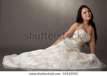  The beautiful young woman in a wedding dress on a grey background