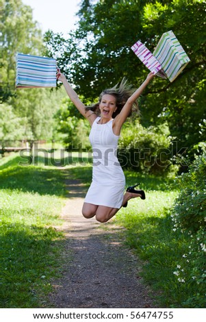 Happy young woman with shopping bags goes home after successful shopping. Outdoors.