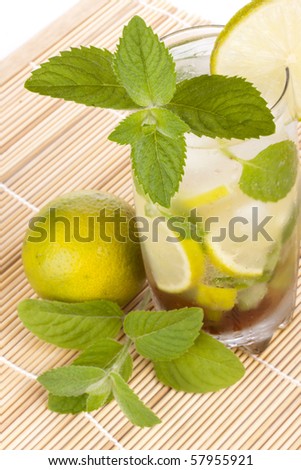 Mojito cocktail with lime, leaves of mint and pieces of ice on a white background