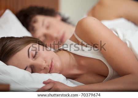 Happy young family sleep in the bed at home.  Selective focus on woman.