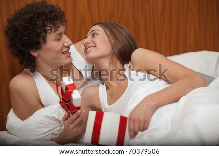 Happy young family with gift box lies in the bed at home. Valentine\'s Day
