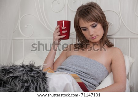 Young beautiful woman reads book in bedroom.
