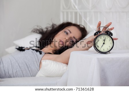 Young sleeping woman and alarm clock in bedroom at home.