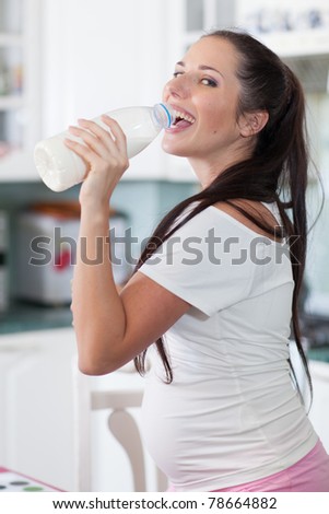 Pregnant woman drinks the milk on the house kitchen.