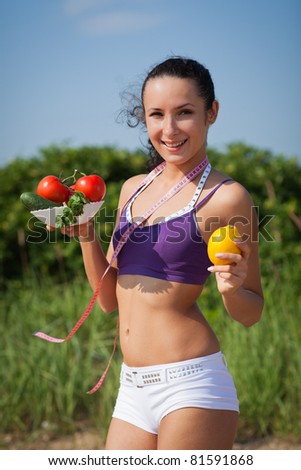 Sporty young woman with measuring tape and vegetables. Outdoors. Concept of healthy lifestyle.