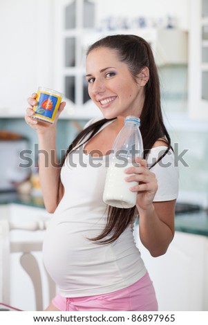 Pregnant woman drinks the milk on the house kitchen.