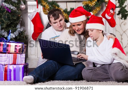 Happy family with notebook sitting near Christmas tree at home.