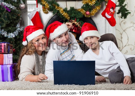 Happy family with notebook sitting near Christmas tree at home.