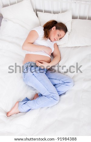 Young pregnant  woman sleeps in bed at home.