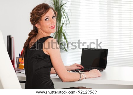 Young businesswoman with laptop sits at the table at the office.