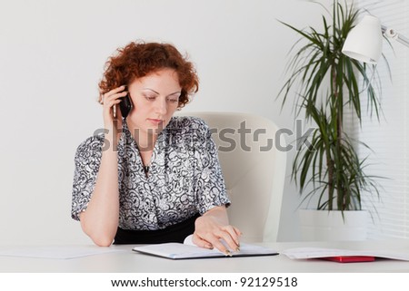Businesswoman with mobile phone sits in the office.