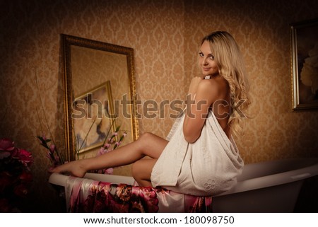Young woman wiping body by a towel in house  bathroom. Concept  of body care.