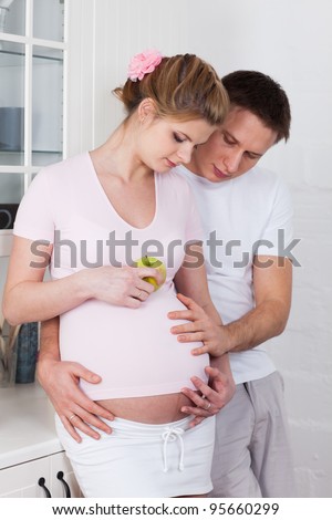 The happy pregnant woman with the husband on the  house kitchen.