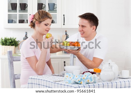 Happy pregnant family with fresh  fruit  on the  house kitchen.