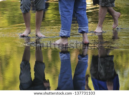 The feet of three men cooling off in puddle.