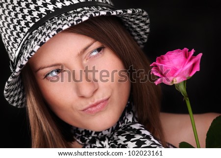A picture of a beautiful woman looking at a pink rose against black background