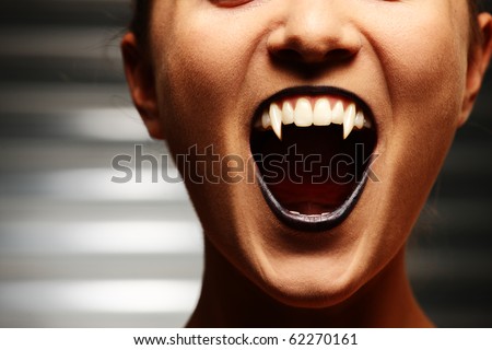 Close up of a vampire woman\'s mouth over dark background