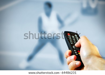 A picture of a male hand holding a remote control over tennis game