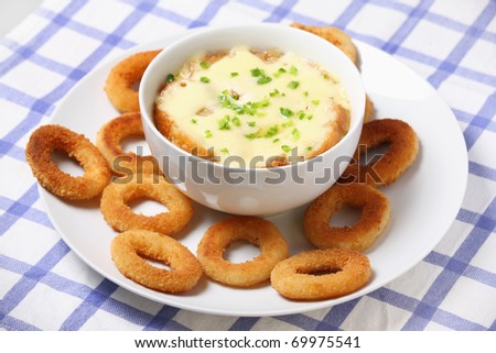 A picture of a bowl of fresh french onion soup baked with toast and cheese and onion rings