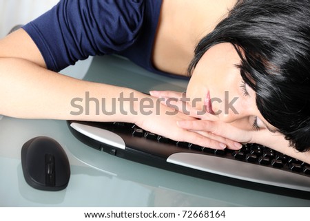A portrait of a young tired woman sleeping on the keyboard at work