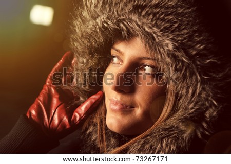 A picture of a nice woman with a fur hood over black and dark background